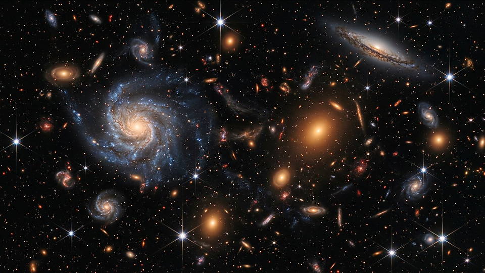 Illustration photoréaliste en lien avec la fiche « La relation distance-vitesse des galaxies a été mise en évidence observationnellement. » : Champ profond de galaxies lointaines, spirales et elliptiques semées dans le noir.